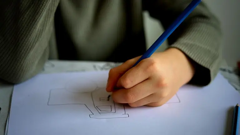 Leerling tekent met een blauw potlood een ontwerpschets op wit papier